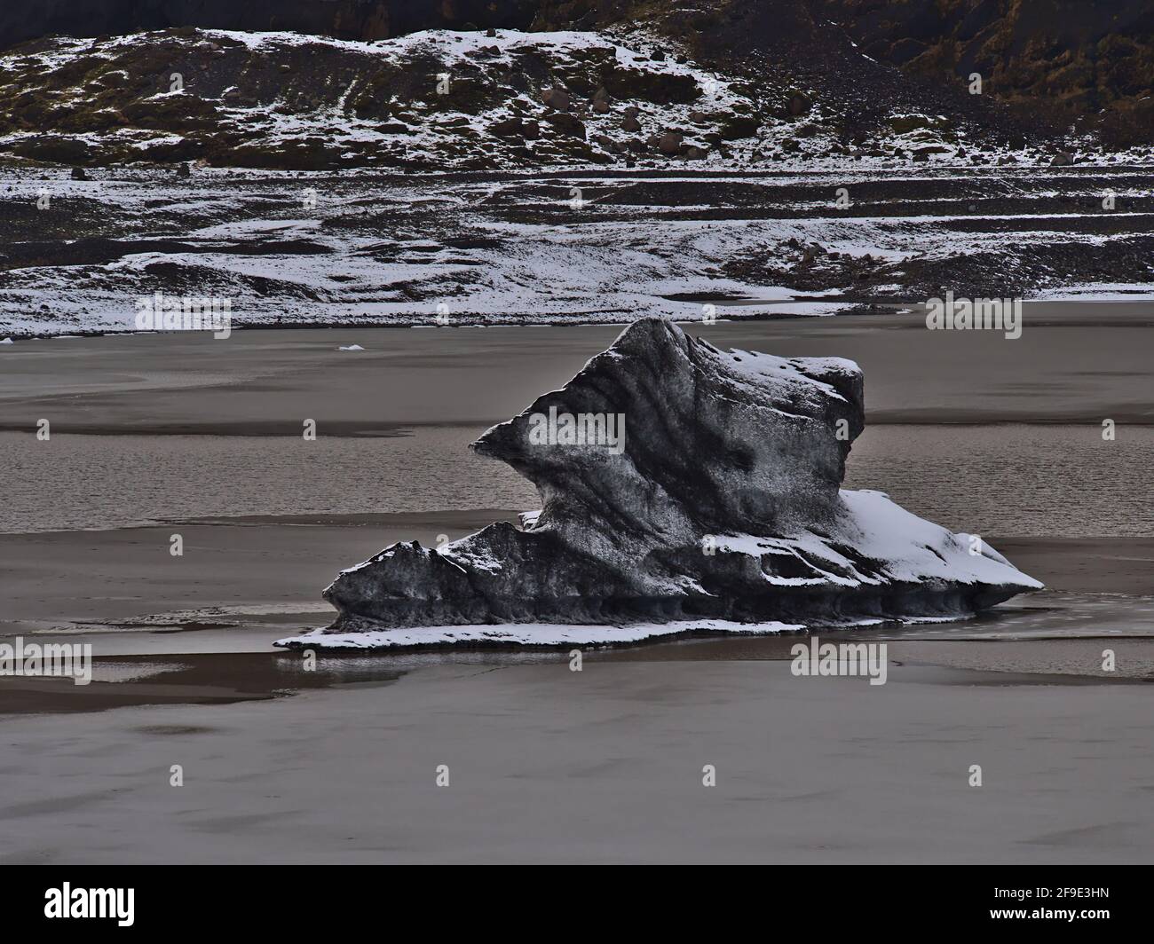 Bizarre Landschaft mit schwarz-weiß gemusterten Eisbergen, die im Gletschersee des Gletschers Sólheimajökull, Teil von Mýrdalsjökull, in Island schweben. Stockfoto