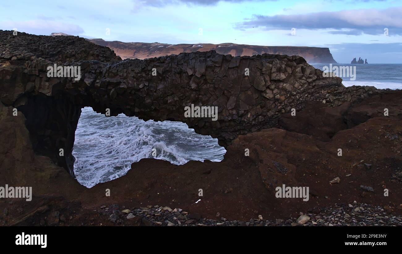 Atemberaubende Aussicht auf einen natürlichen Felsbogen aus vulkanischem Basalt an der Atlantikküste im Süden Islands in der Nähe der Ringstraße auf der Halbinsel Dyrhólaey mit rauem Meer. Stockfoto