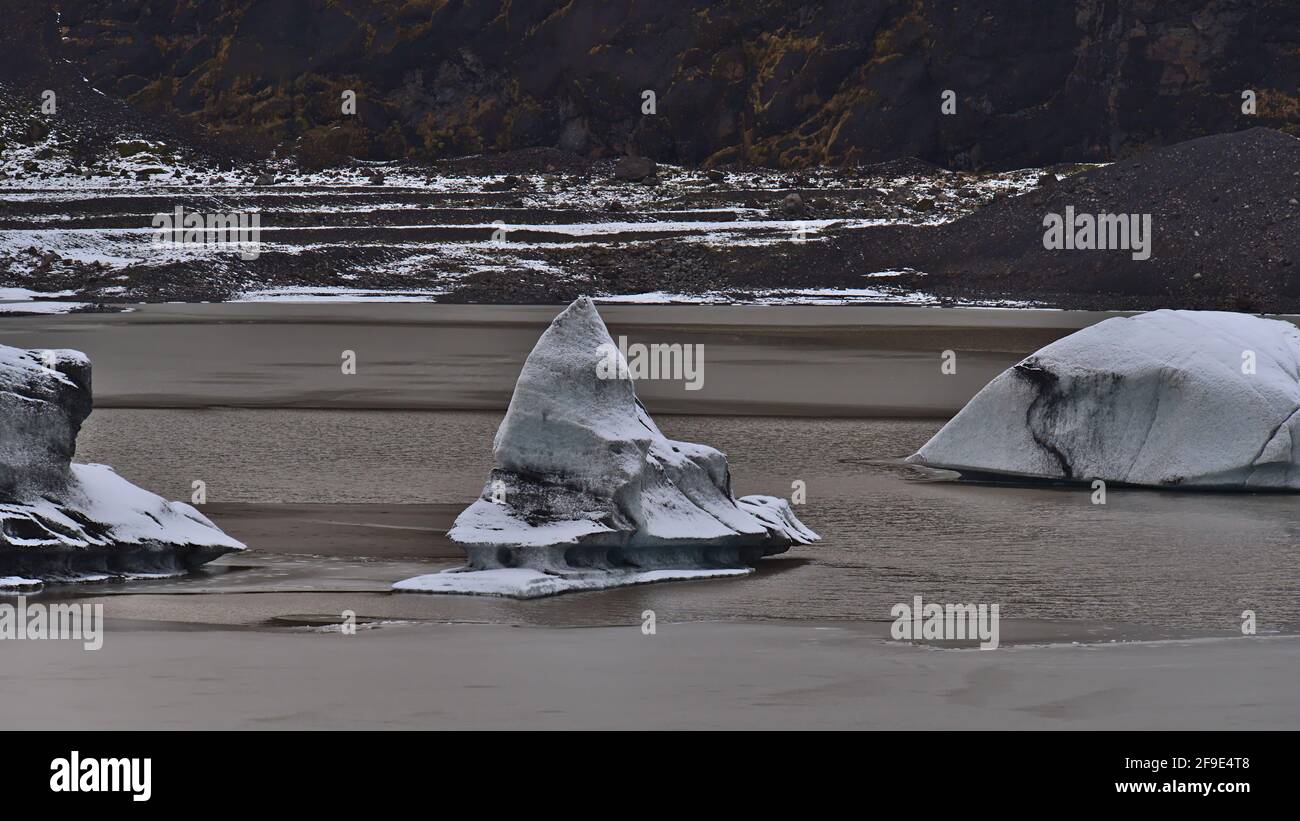 Nahaufnahme von bizarr aussehenden Eisbergen mit weißen und schwarzen Texturen, die im Gletschersee von Sólheimajökull, einem Auslaufgletscher von Mýrdalsjökull, schweben. Stockfoto