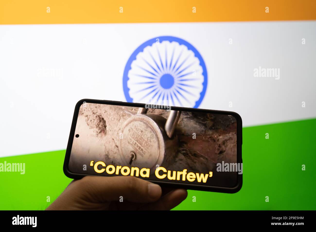 Mann, der ein Mobiltelefon mit Nachrichten auf Corona-Ausgangssperre hält Und die dreifarbige Flagge indiens im Hintergrund Die Selbstverriegelung während der zweiten Stufe Stockfoto