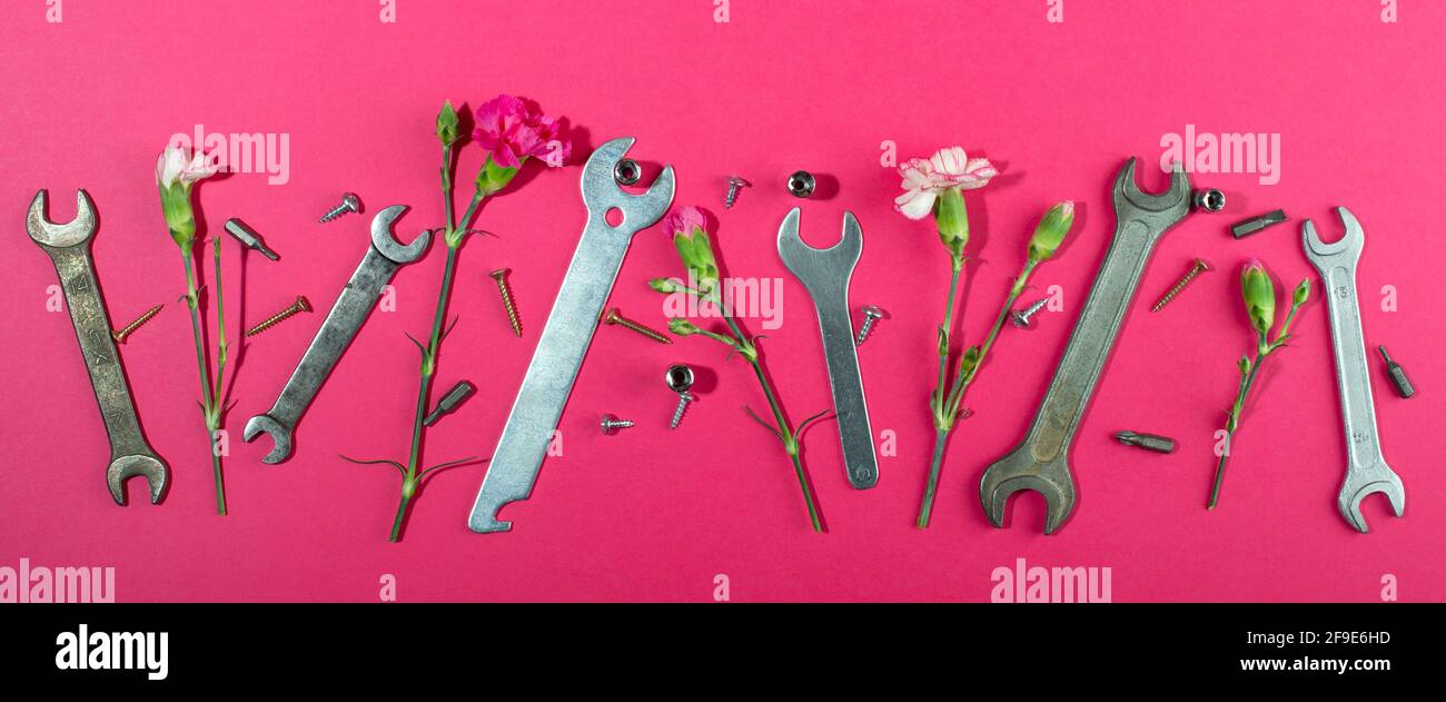 Labor Day Hintergrundkonzept, 1. Mai Konzept. Schlüssel und Nelke rosa Nelke Blume auf rosa Hintergrund. Flach liegend, Draufsicht. Banner. Stockfoto