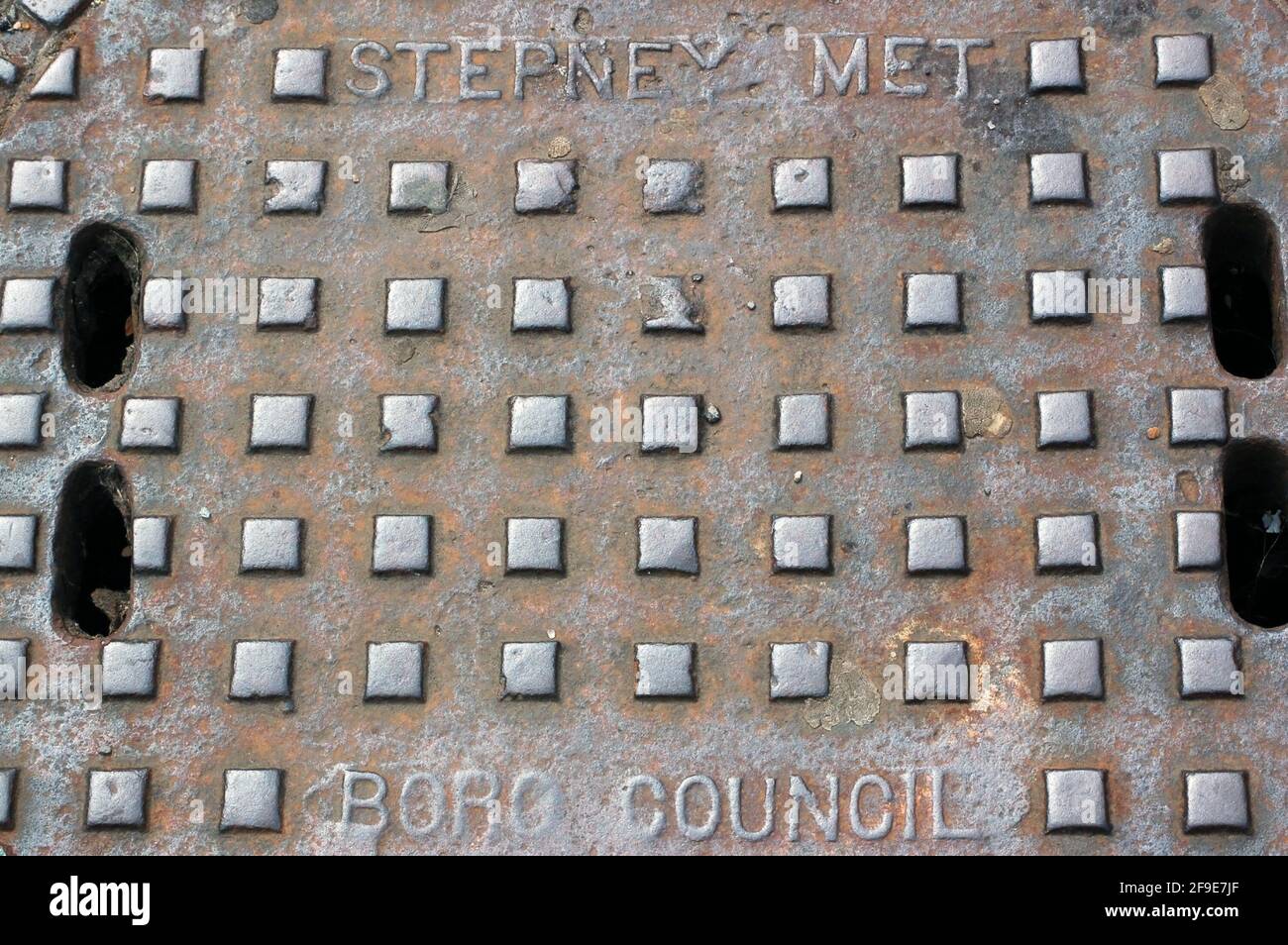 Die gusseiserne Schachtabdeckung ist mit dem jetzt nicht mehr existierenden Stepney Metropolitan Borough Council in London gekennzeichnet. Stockfoto