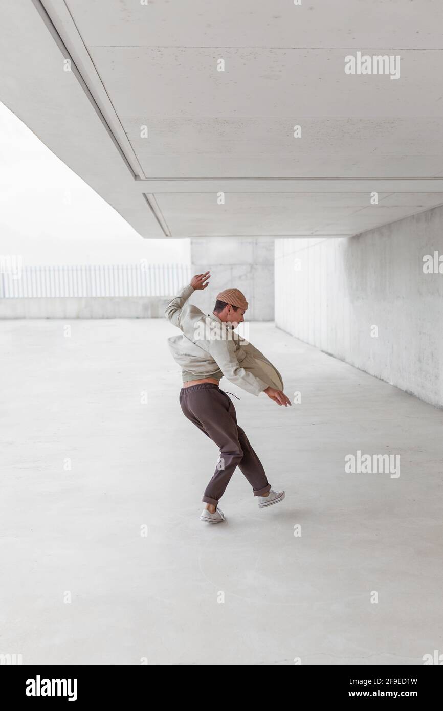 Seitenansicht eines talentierten männlichen Tänzers beim Breakdancing in einer geräumigen Passage Im Stadtgebiet Stockfoto