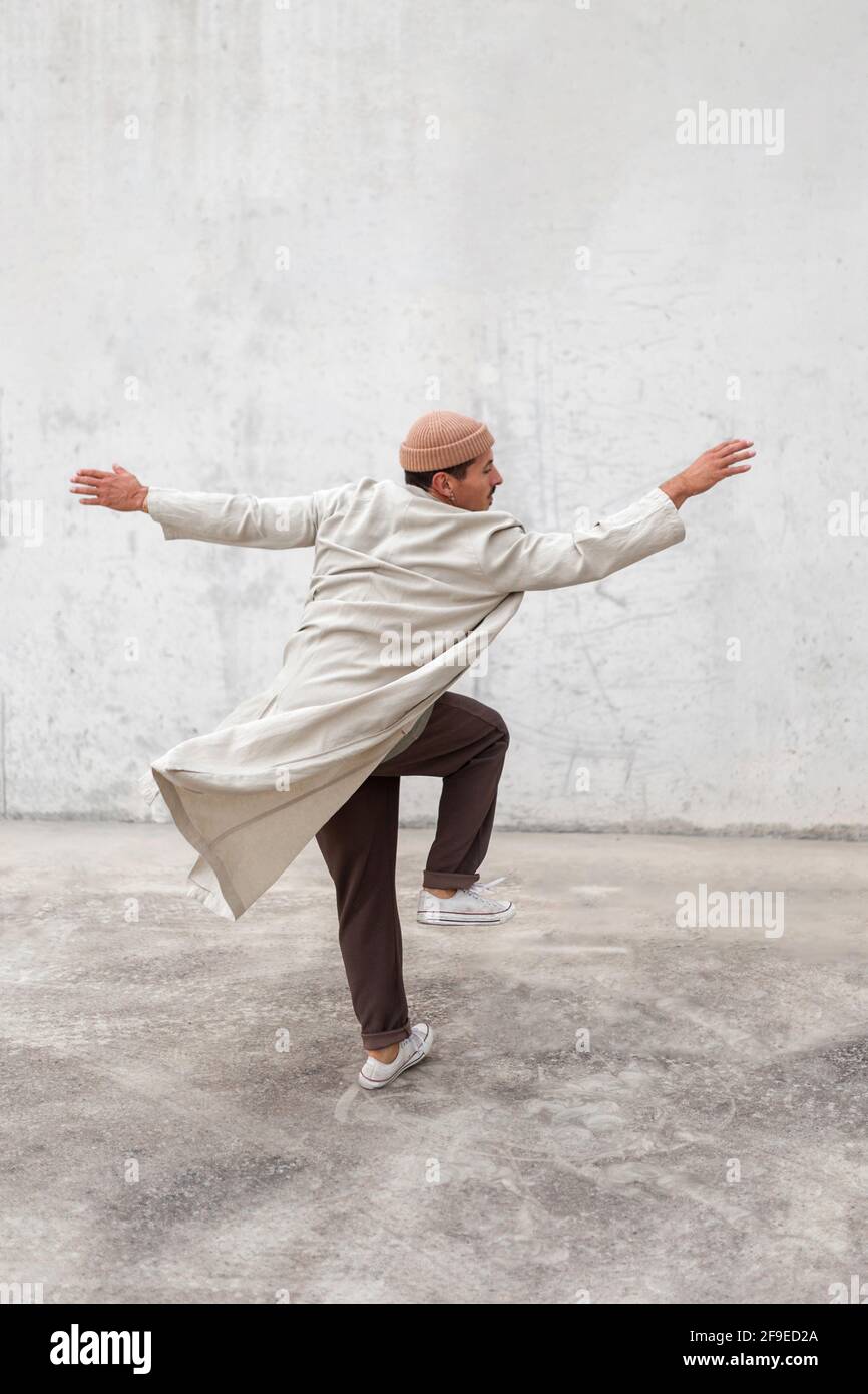 Rückansicht eines anonymen männlichen Breakdancers, der in der Stadt auftrat Bereich in der Nähe der grauen Gebäudewand Stockfoto