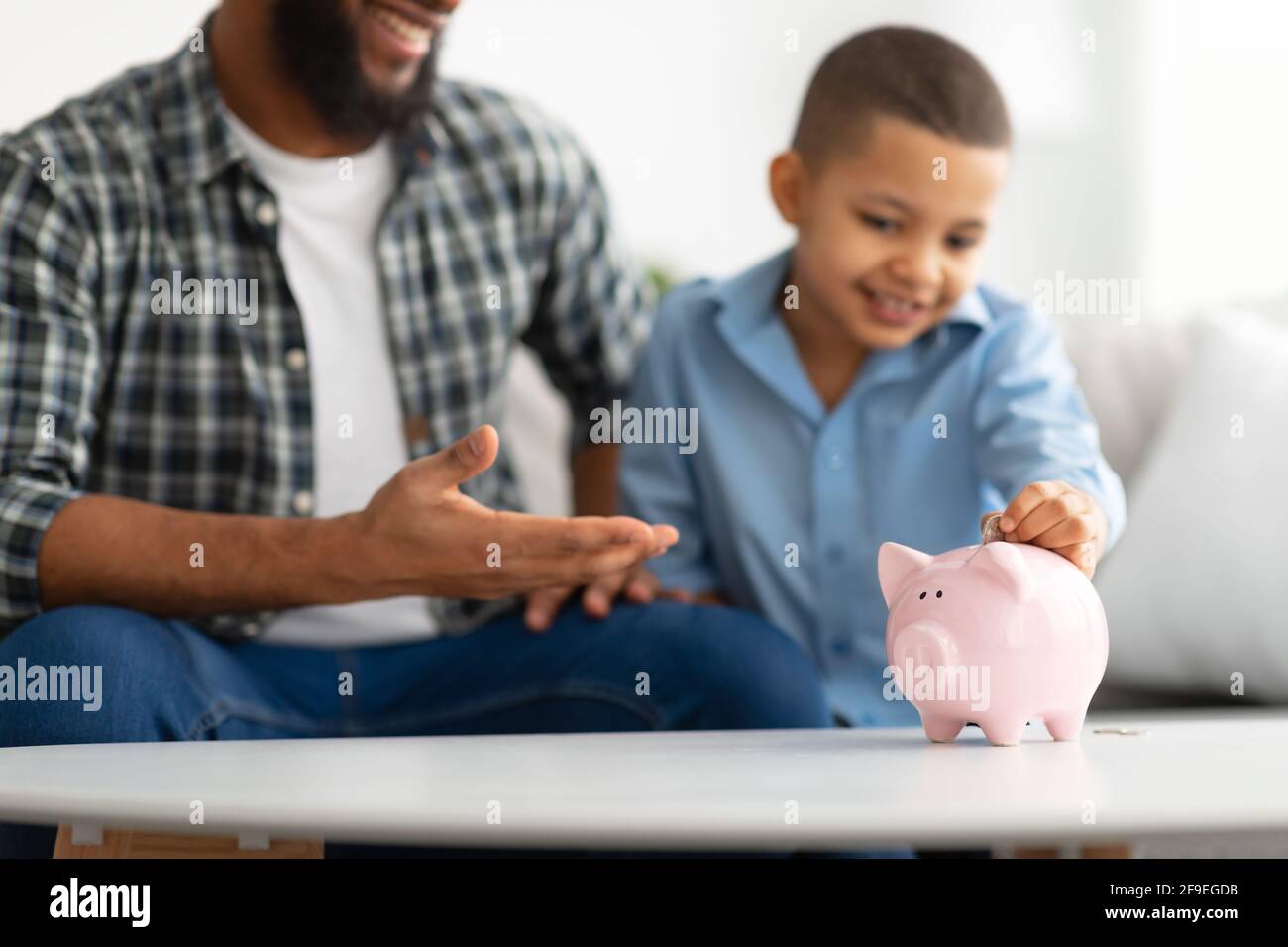 Vater Und Sohn Setzen Persönliche Ersparnisse In Sparschwein Innen, Abgeschnitten Stockfoto