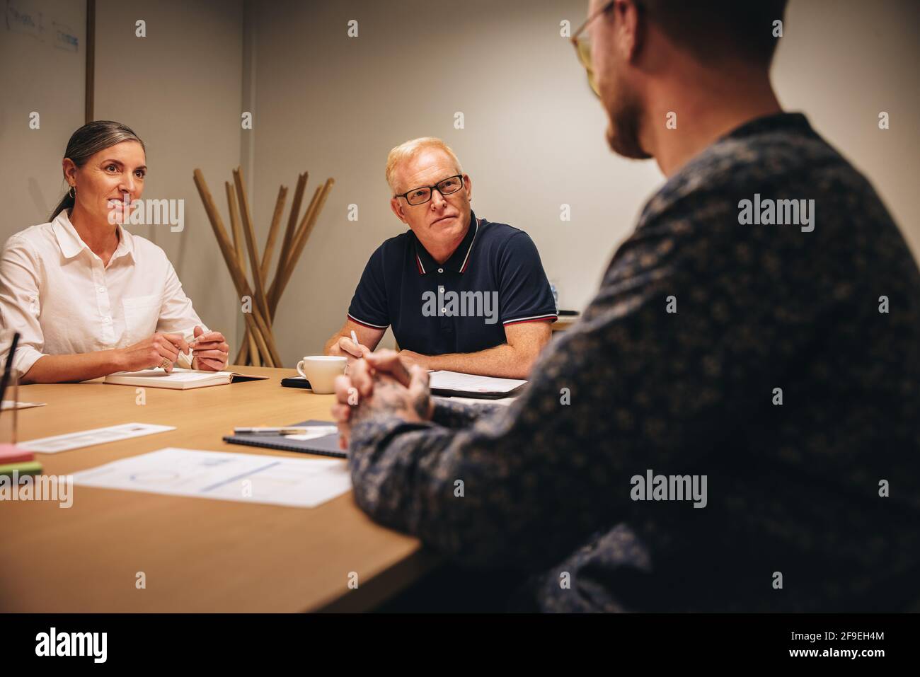 Zwei Geschäftsleute, die ein Vorstellungsgespräch mit einem Mann in der Vorstandssitzung machen. Geschäftspartner interviewen neue Kandidaten im Amt. Stockfoto