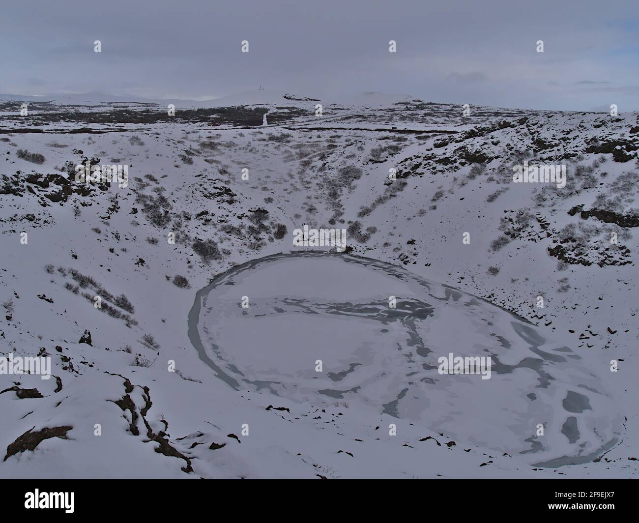 Blick auf den gefrorenen Vulkankrater-See Kerið (auch Kerid, Kerith) in Grímsnes, Island, Teil des Goldenen Kreises, mit schneebedeckten Hängen im Winter. Stockfoto