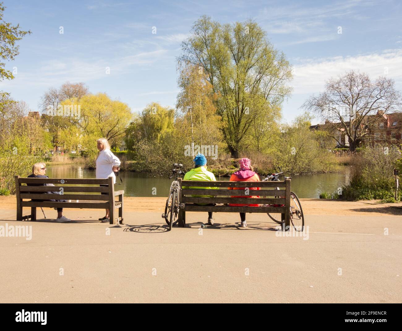 Menschen, die auf einer Parkbank sitzen und die Landschaft am Barnes Pond im Südwesten Londons, Großbritannien, genießen Stockfoto