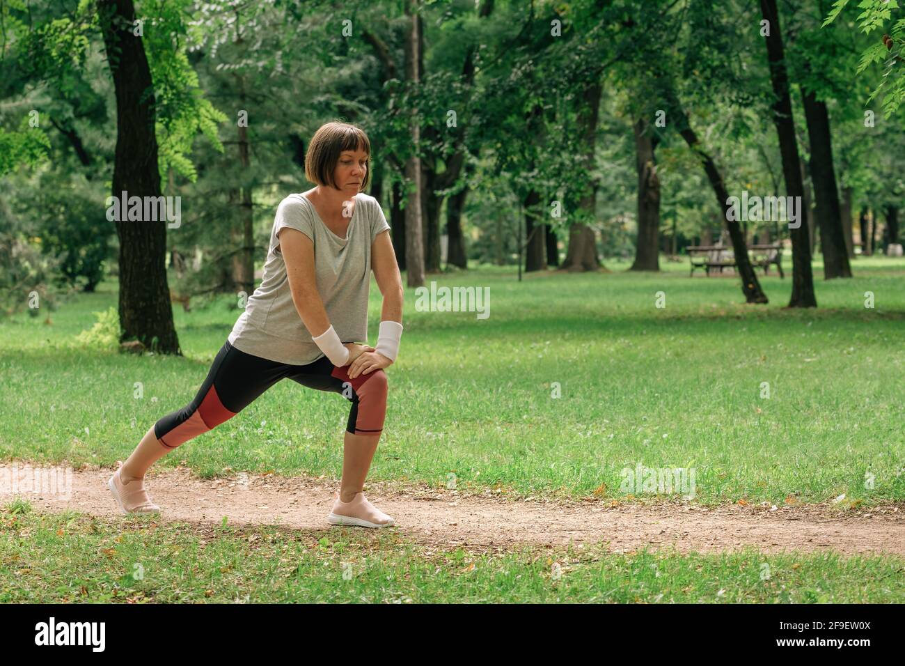 Weibliche Jogginghose, die Muskeln dehnt und sich zum Laufen im Park aufwärmt, selektiver Fokus Stockfoto