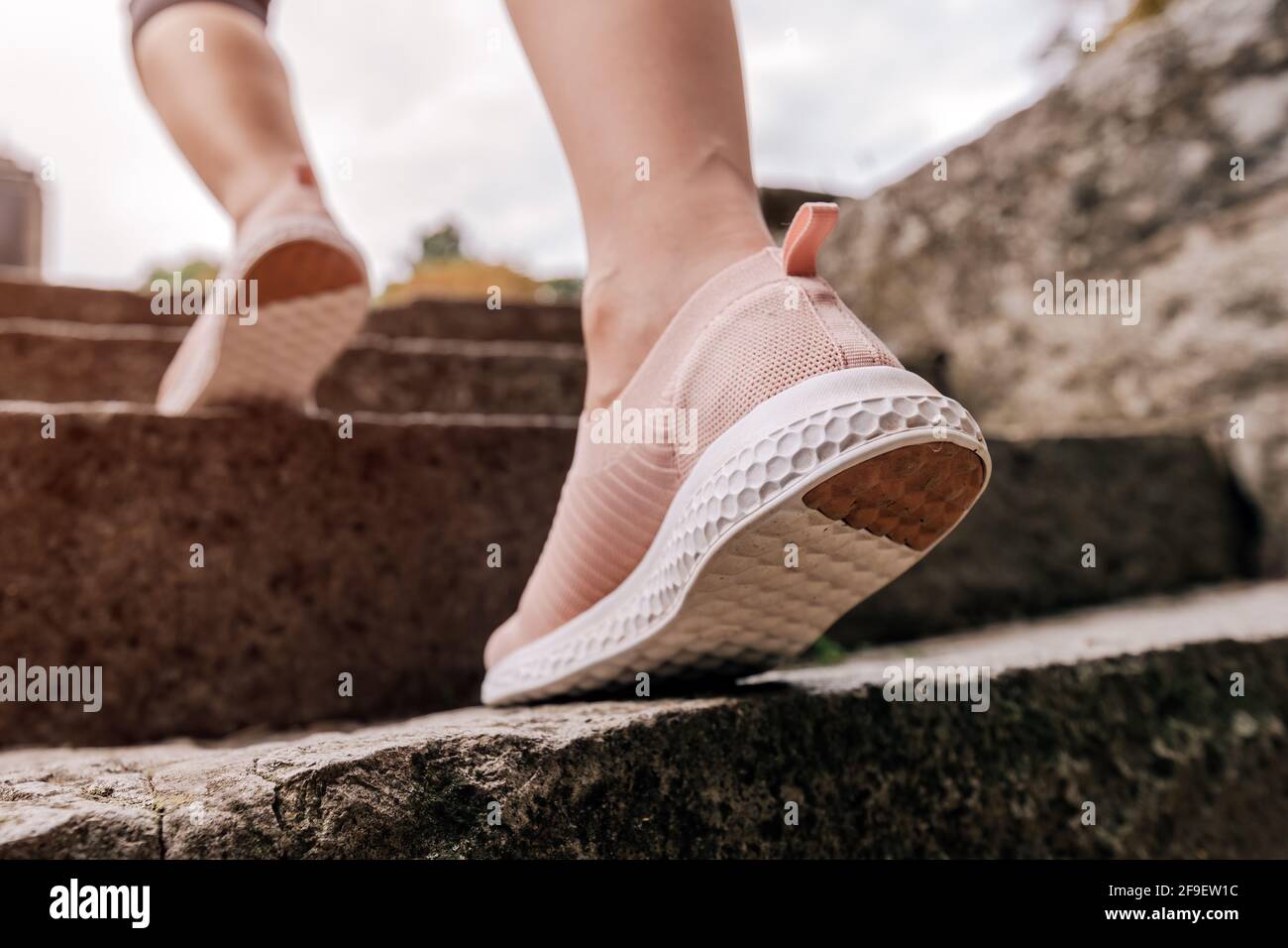 Jogginghose, die sich für das Training aufwärmt, indem sie im Park die Treppe hochläuft, Nahaufnahme mit selektivem Fokus und Bewegungsunschärfe-Effekt Stockfoto