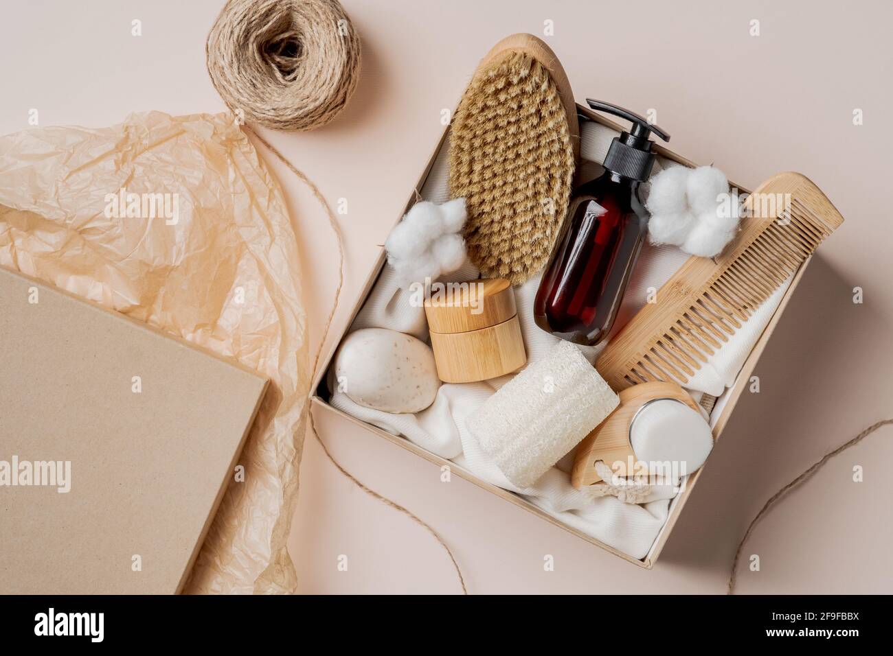 Beauty-Box mit natürlicher Körperpflegekosmetik. Körperbürste, Haarkur, Bernstein-Glas-Shampoo-Flasche, Feuchtigkeitscreme, Baumwolle. Flach liegend, Draufsicht. Stockfoto