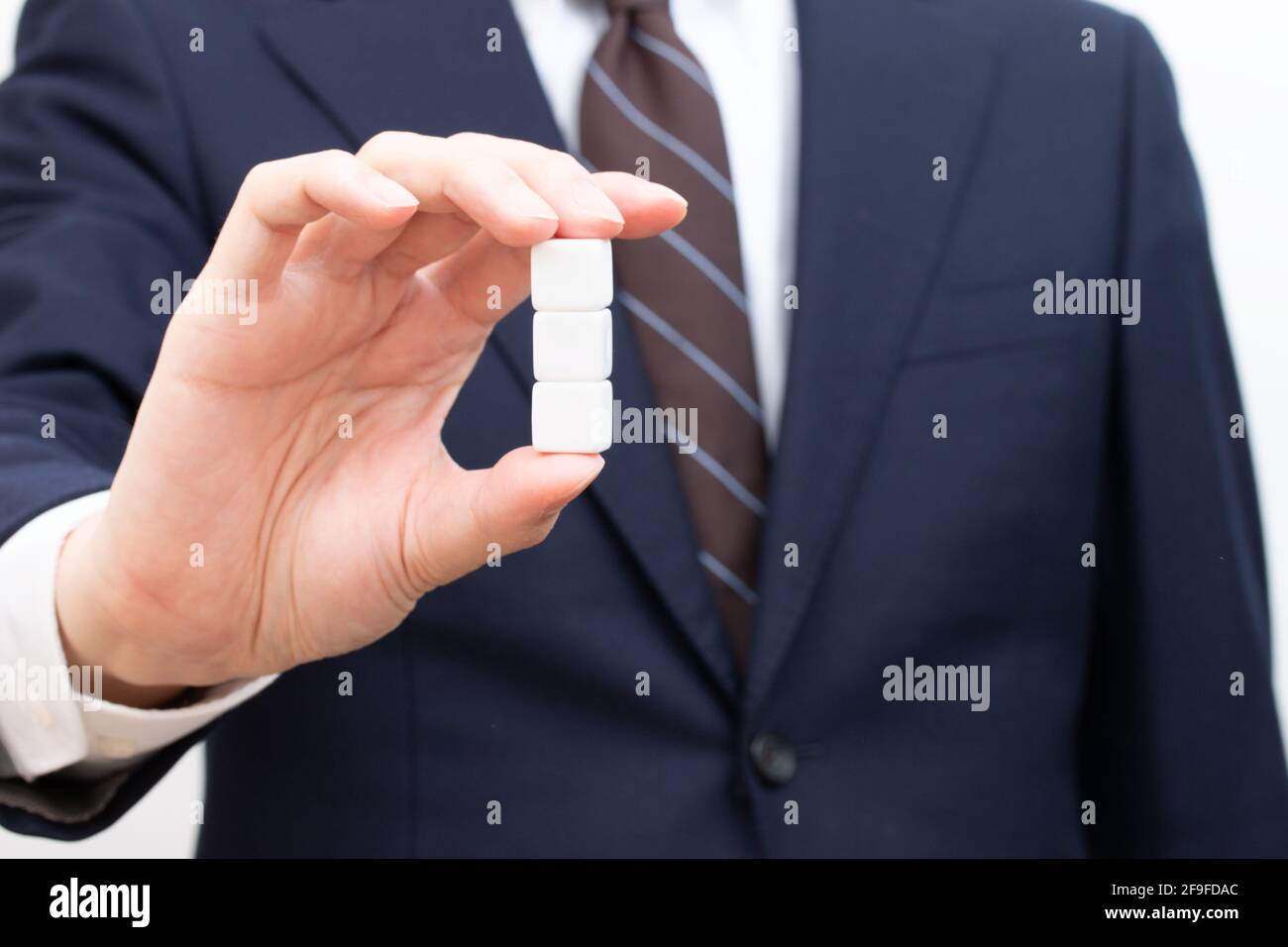 Drei weiße Würfel, die von einem Mann in einem Anzug gehalten werden Stockfoto