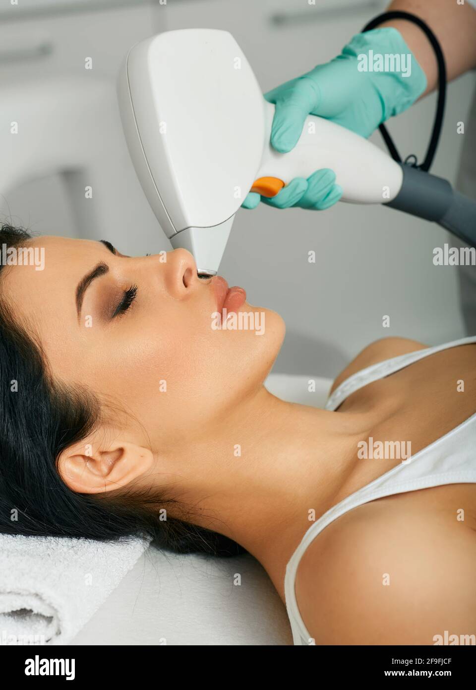 Gesichtslaser Haarentfernung. Schöne Frau während der Laser-Haarentfernung und Laser-Epilation auf den Lippen Bereich auf ihrem Gesicht Stockfoto