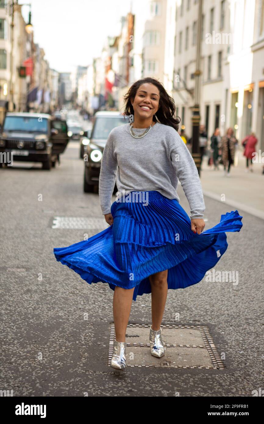 Ein Modell mit einem grauen H&M-Pullover, der mit einem blauen langen  Anthropologie-Rock und silbernen Bershka-Schuhen verziert ist, die während  eines Fotoshootings im Straßenstil in der Bond Street, London, zu sehen  waren Stockfotografie -