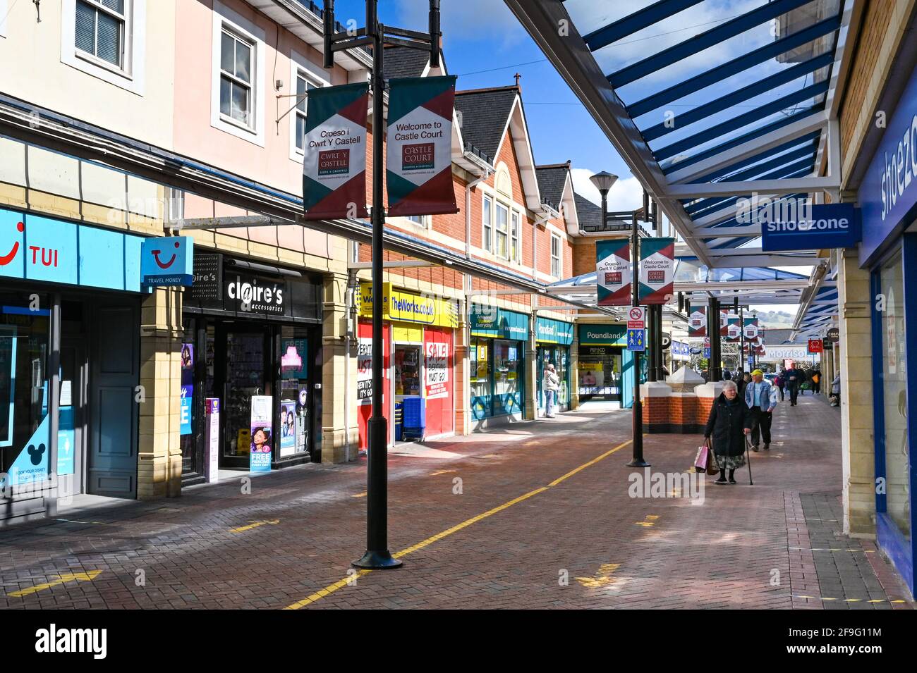 Caerphilly, Wales - April 2021: Menschen, die im Castle Court Einkaufszentrum in der Stadt Caerphilly in Südwales an Geschäften vorbeilaufen. Stockfoto