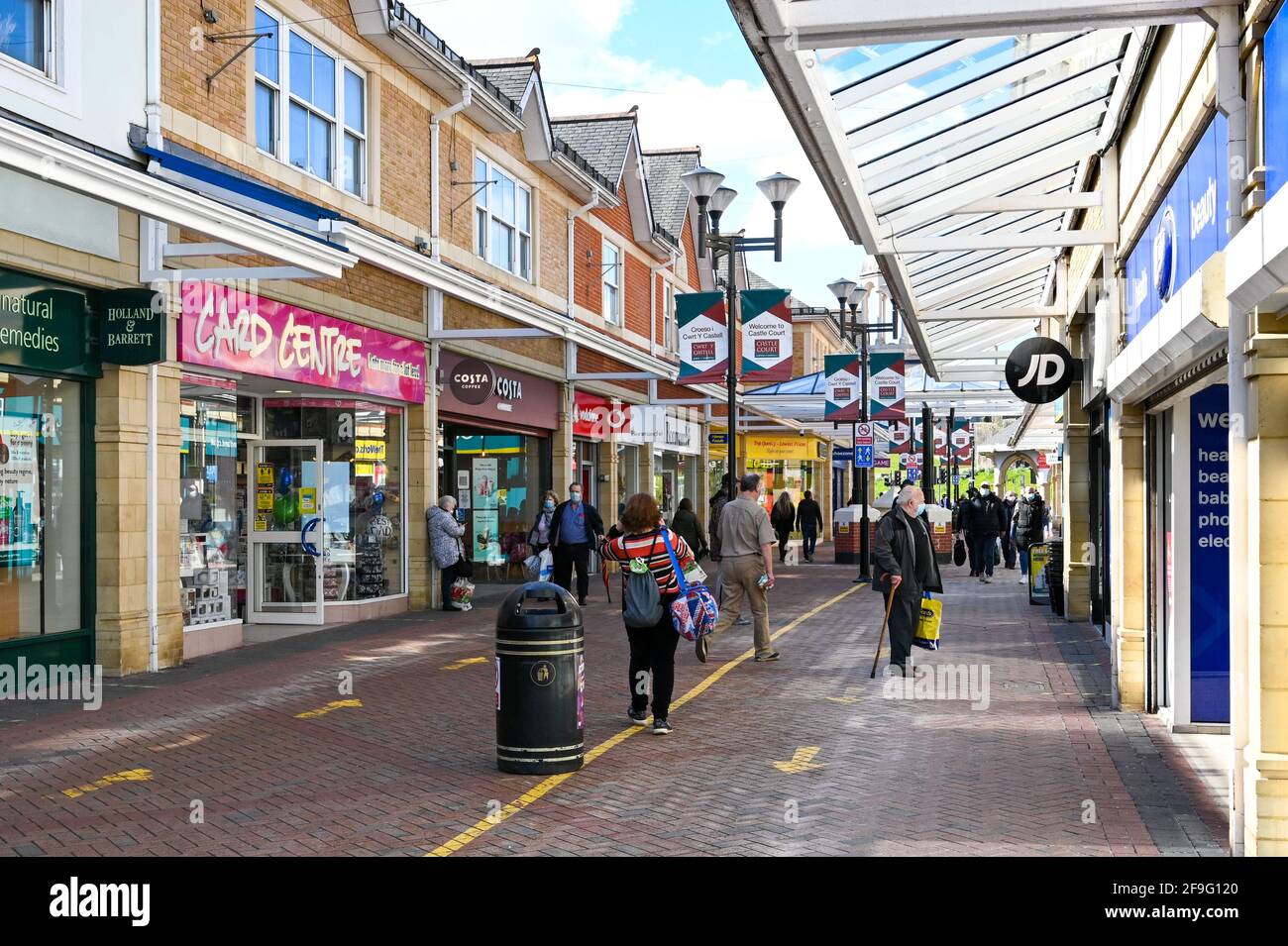 Caerphilly, Wales - April 2021: Menschen, die im Castle Court Einkaufszentrum in der Stadt Caerphilly in Südwales an Geschäften vorbeilaufen. Stockfoto
