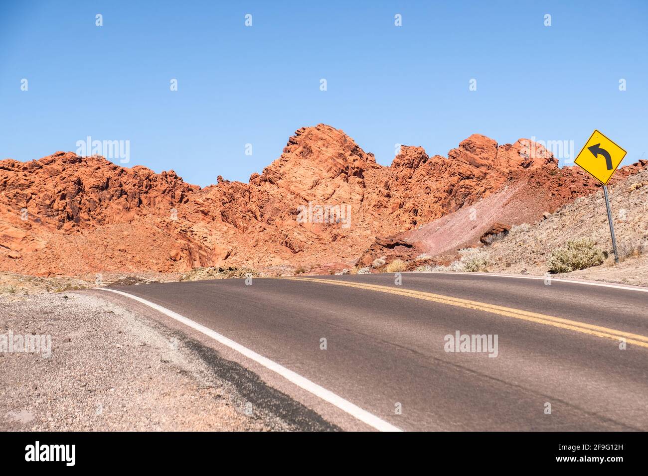 Biegen Sie links vor dem Verkehrsschild am leeren Highway nach Red ab Azteken-Sandstein- und Gesteinsformationen im Valley of Fire State Park in Nevada Stockfoto