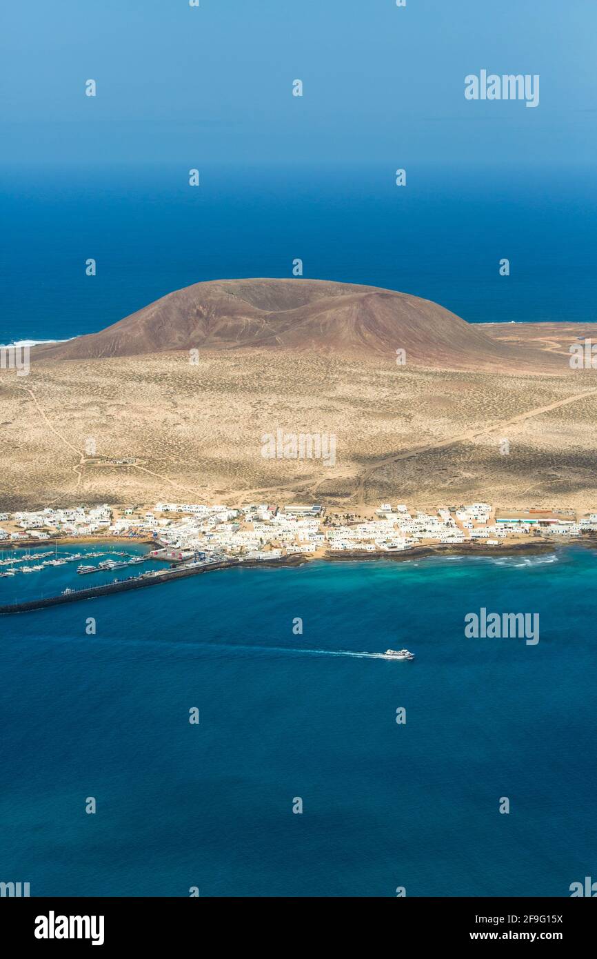 Haría, Lanzarote, Kanarische Inseln, Spanien. Blick auf La Graciosa vom Mirador del Río, Fähre verlässt den Hafen von Caleta de Sebo. Stockfoto