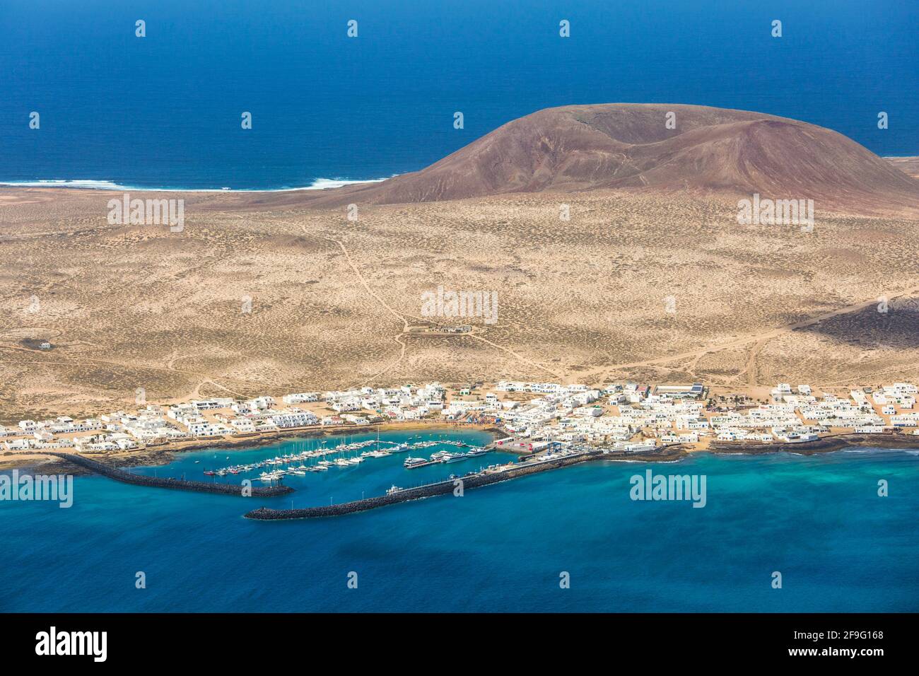 Haría, Lanzarote, Kanarische Inseln, Spanien. Blick vom Mirador del Río auf den Hafen von Caleta de Sebo, La Graciosa. Stockfoto