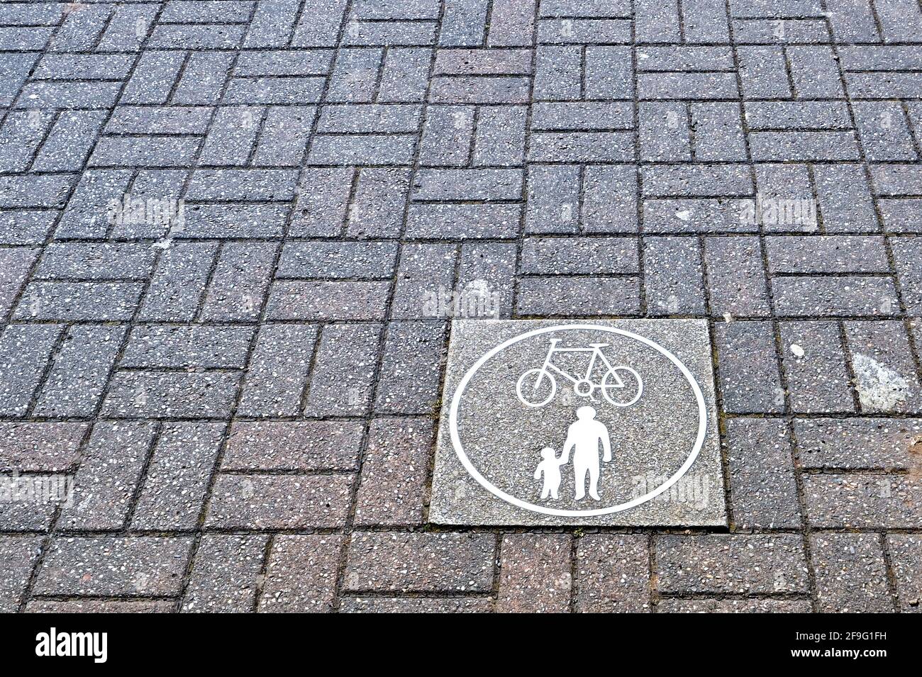 Plakette auf einem gepflasterten Weg mit Symbolen, die die Verwendung für Radfahrer und Fußgänger zeigen. Keine Personen. Stockfoto