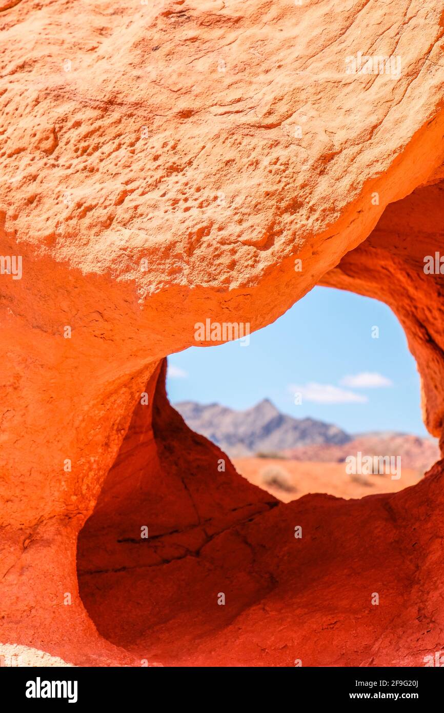 Far Away Mountain vom Natural Look Through Hole On aus gesehen Red Aztec Sandstein und Felsformation im Valley of Fire State Park in Nevada in der Nähe von Las Vegas Stockfoto
