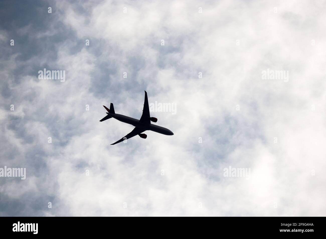 Silhouette eines Flugzeugs, das in blauem Himmel mit weißen Wolken fliegt. Passagierflugzeug am Flug, Reisekonzept Stockfoto