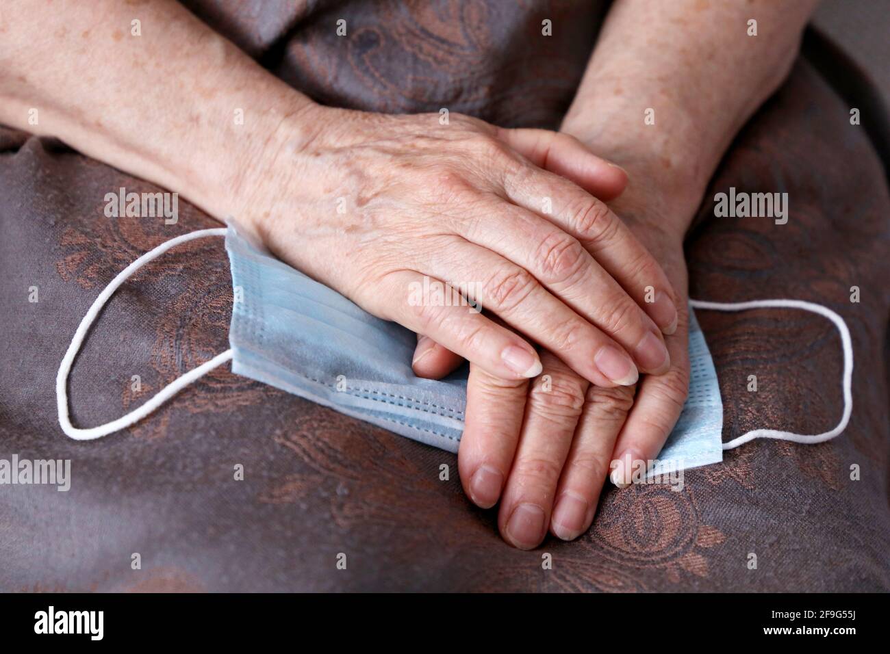 Faltige Hände älterer Frau mit medizinischer Gesichtsmaske. Coronavirus-Schutz für alte Menschen Stockfoto