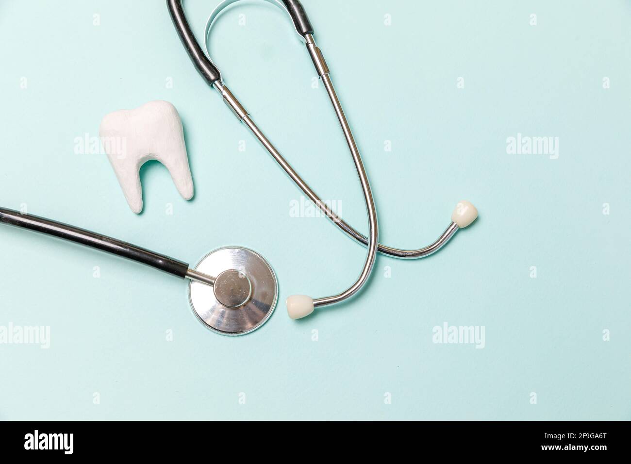 Gesundheit Zahnpflege Konzept. Medizingeräte Stethoskop weiß gesunden Zahn auf pastellblauem Hintergrund isoliert. Instrumentengerät für Zahnarztdocto Stockfoto