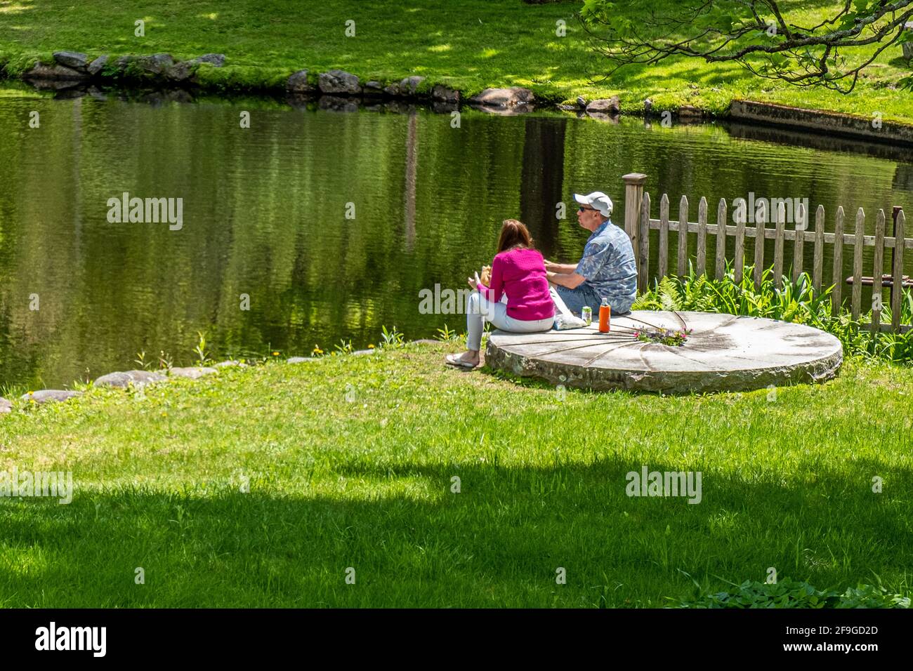 Ein Paar, das auf einem alten Mühlrad in der Nähe eines Mühlenteiches in Petersham, Massachusetts, sitzt Stockfoto