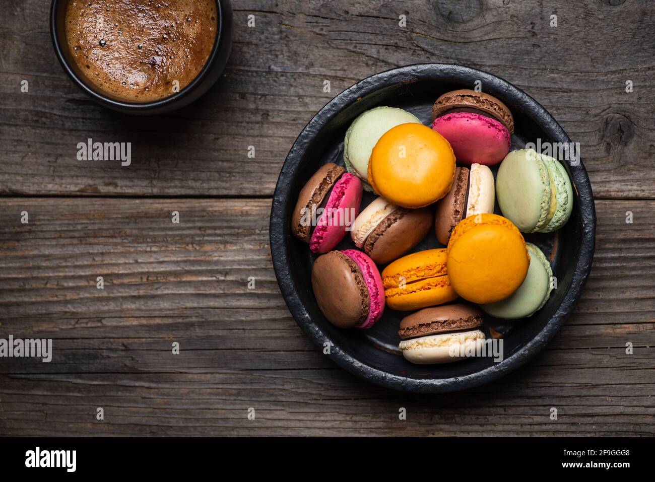 Macaron oder Makronen süße Plätzchen Desserts und eine Tasse Kaffee auf einem Holztisch, Tischansicht Stockfoto