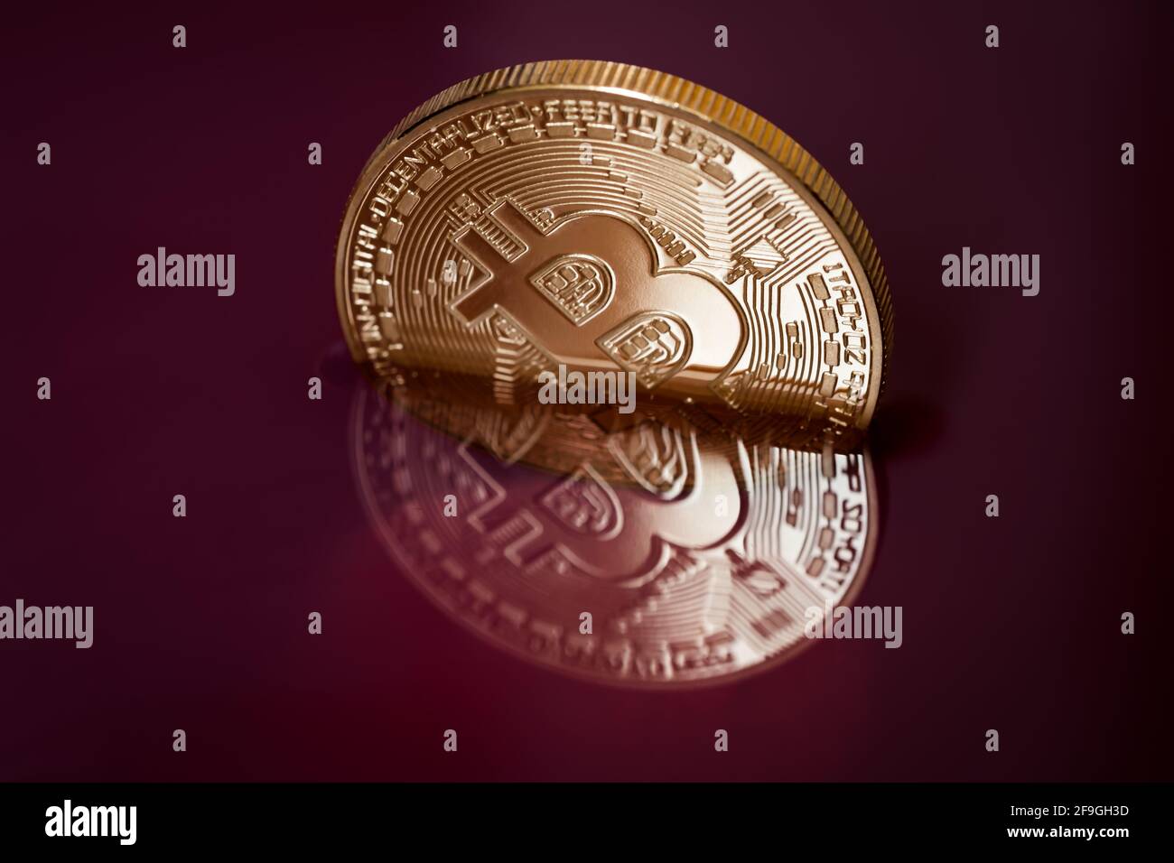 Kryptowährung in roter Flüssigkeit. Bitcoin unter Wasser. Der Untergang einer goldenen Münze. Stockfoto