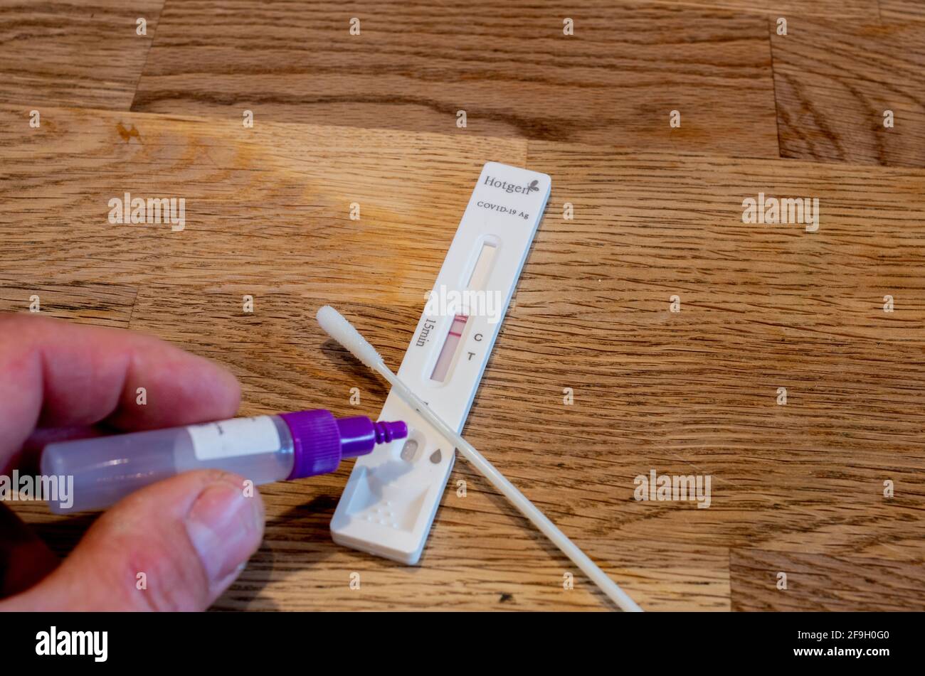 Bamberg, Deutschland - 8.4.2021. Antigen-Testprobe wird von Hand auf das Gerät des Herstellers Hotgen abgeworfen. Stockfoto