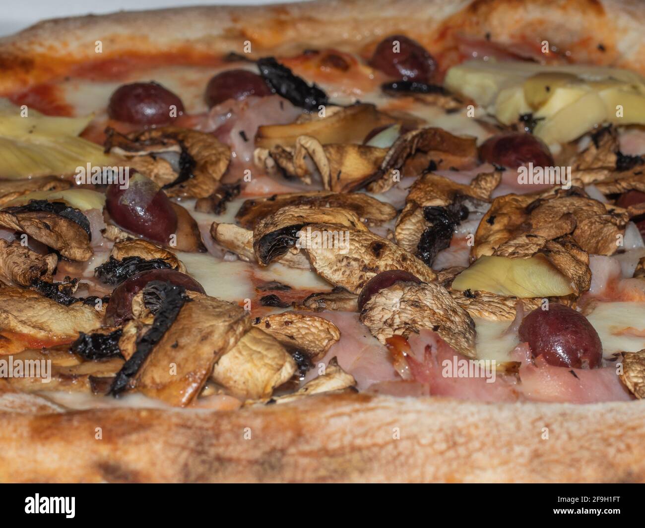 Detail einer Pizza mit Tomaten, Mozzarella, Oliven, Artischocken und Pilzen Stockfoto