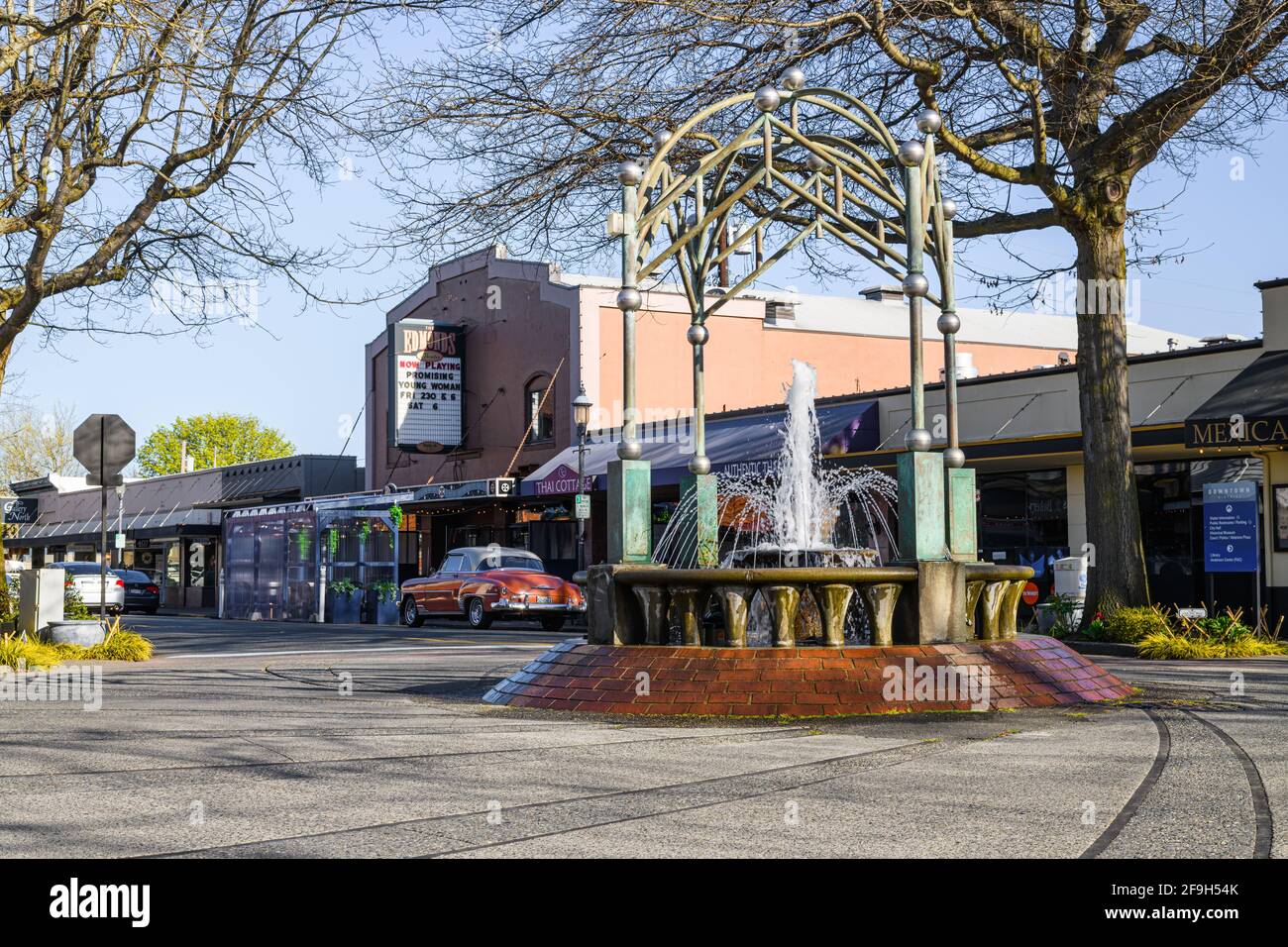 Die zeitlose Szene im Stadtzentrum von Edmonds an einem Frühlingstag findet den Edmonds Cedar Dreams Fountain, der vom Edmonds Theatre unterstützt wird, und einen klassischen Chevrolet Stockfoto