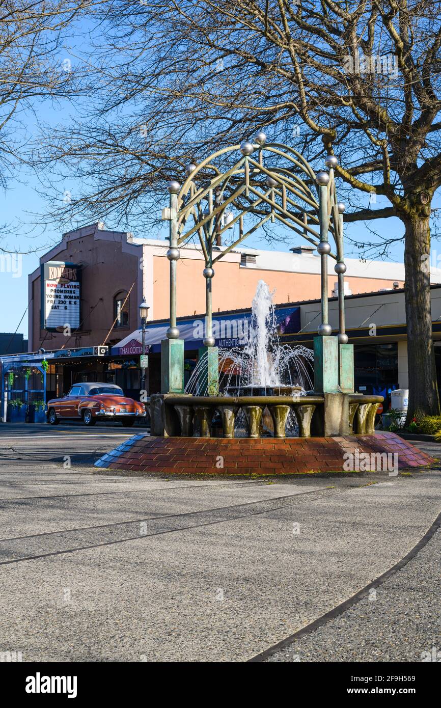 Downtown Edmonds an einem Frühlingstag gibt es den Edmonds Cedar Dreams Fountain mit seinem fließenden Brunnen, der vom Edmonds Theatre und einem klassischen Chevrolet unterstützt wird Stockfoto