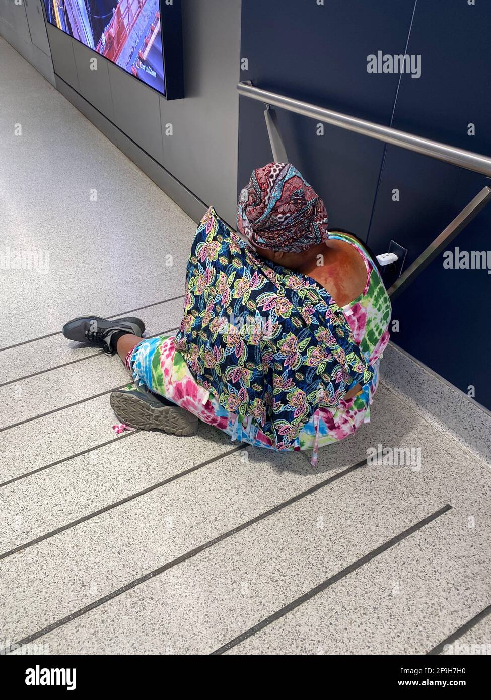 Eine scheinbar obdachlose Frau in farbenfrohem Kleid sitzt an einer Auffahrt zur neuen Moynihan Train Hall am Penn Station in New York City. Stockfoto