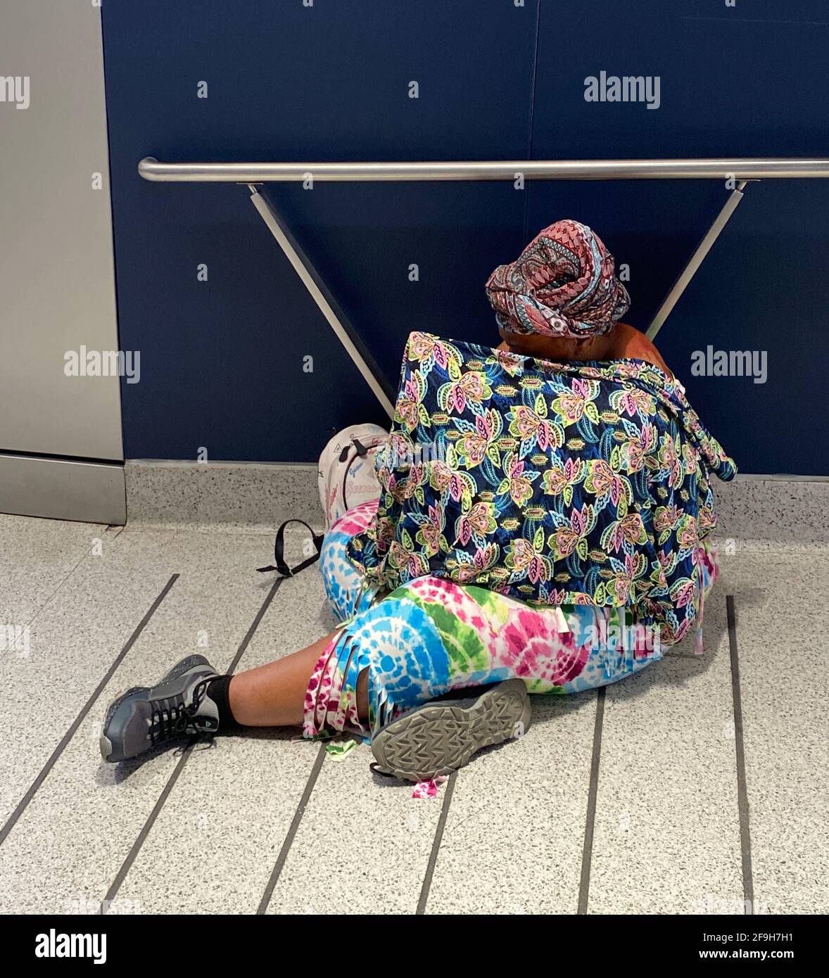 Eine scheinbar obdachlose Frau in farbenfrohem Kleid sitzt an einer Auffahrt zur neuen Moynihan Train Hall am Penn Station in New York City. Stockfoto