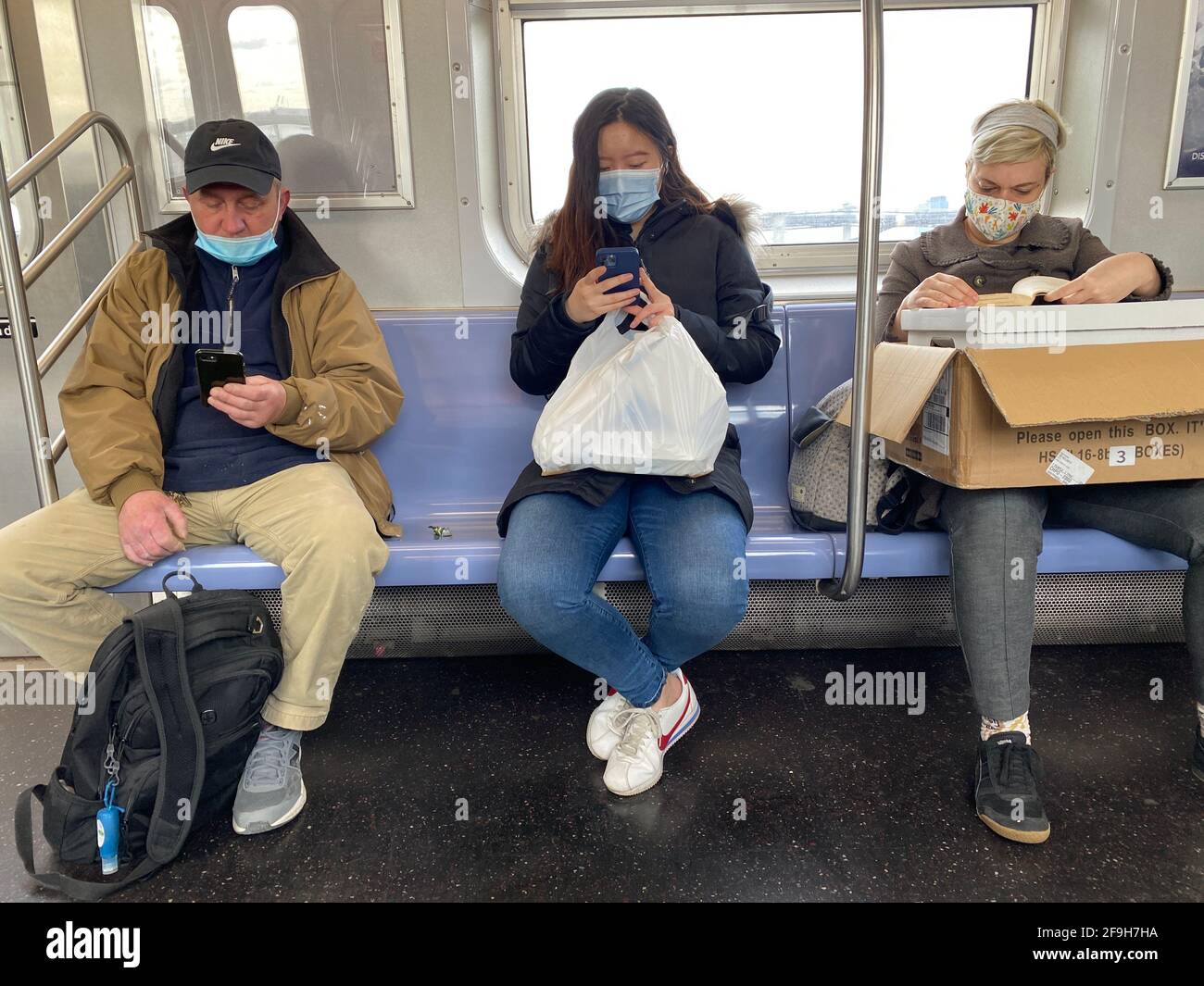 Drei U-Bahnfahrer in Brooklyn während der Covid-19-Pandemie zu Beginn des zweiten Jahres des Virus. Sie scheinen sich nicht zu sehr um soziale Distanzierungen zu sorgen. Stockfoto