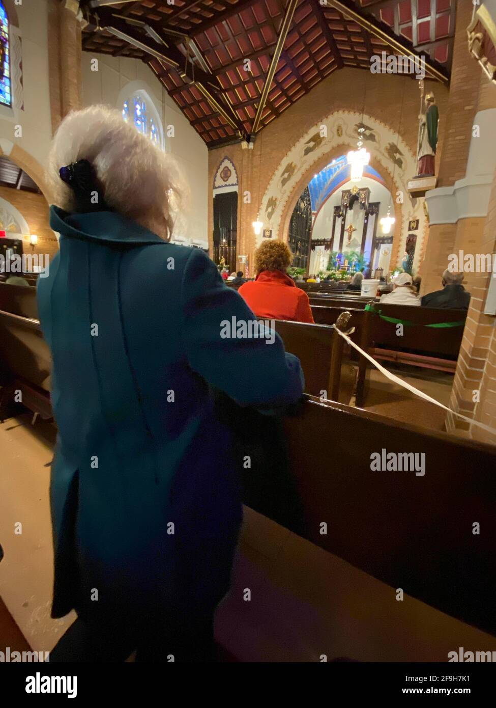 Die Menschen beten in einer katholischen Kirche, wobei jede zweite Reihe von Kirchenbänken abgesperrt ist, um der obligatorischen sozialen Distanzierung in Brooklyn, NY, während der Covid-Pandemie nachzukommen. Stockfoto