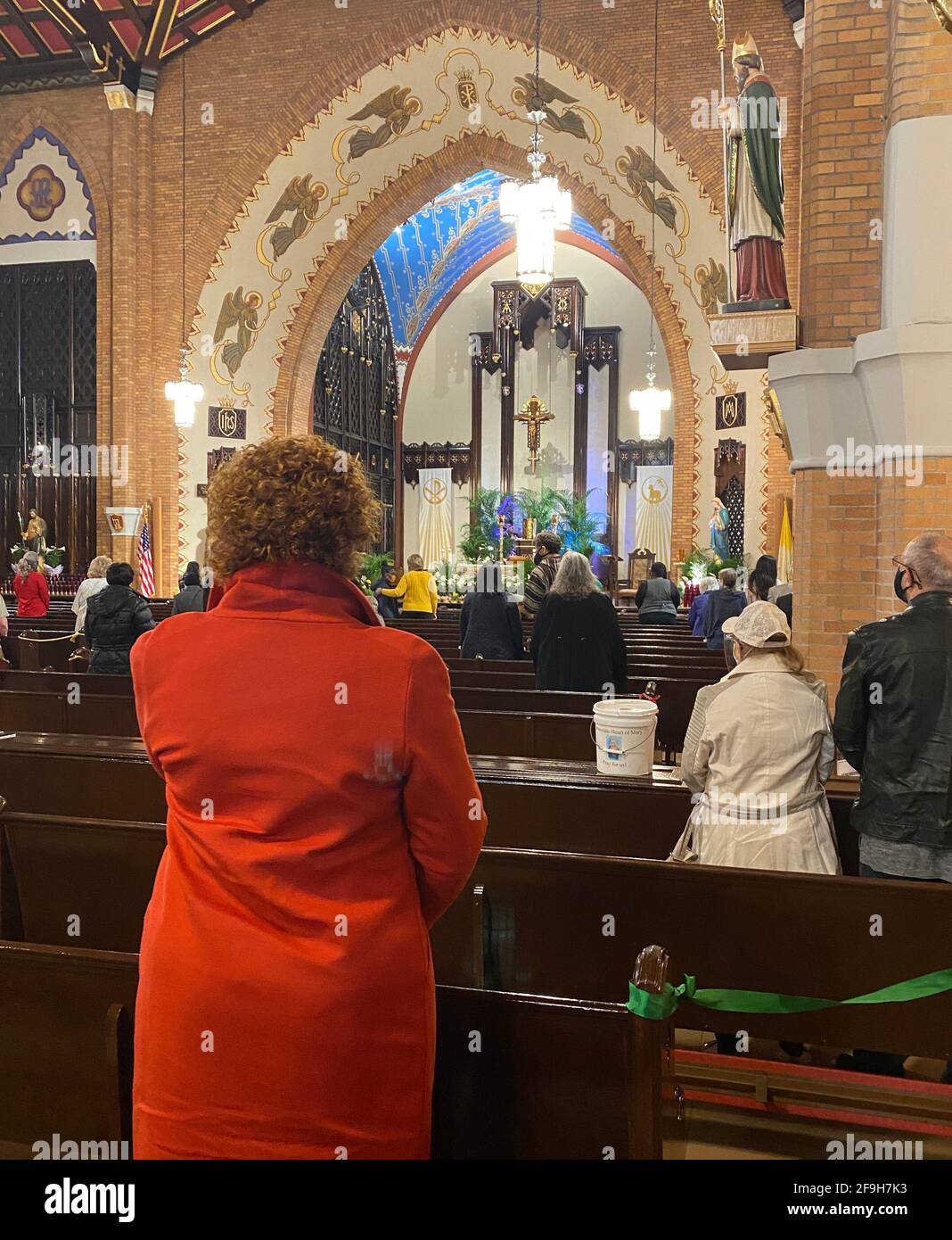 Die Menschen beten in einer katholischen Kirche, wobei jede zweite Reihe von Kirchenbänken abgesperrt ist, um der obligatorischen sozialen Distanzierung in Brooklyn, NY, während der Covid-Pandemie nachzukommen. Stockfoto