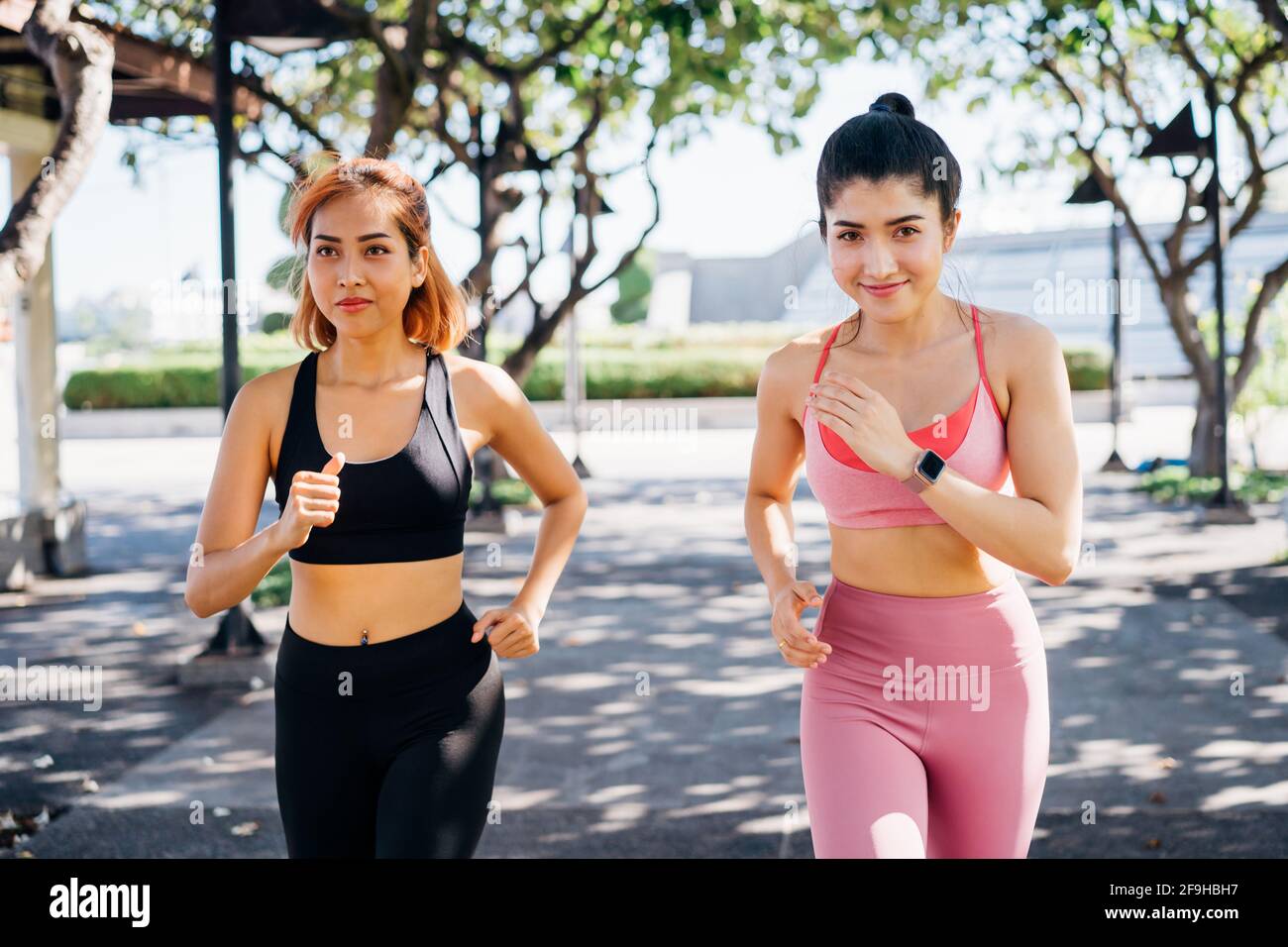 Glückliche asiatische Freundinnen in Sportswear beim Laufen und Joggen Outdoor-Park für einen gesunden Lebensstil Stockfoto