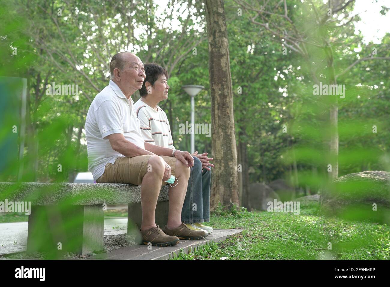 Ein asiatisches Senioren-Paar sitzt auf einer Bank im Park. Speicherplatz kopieren. Stockfoto