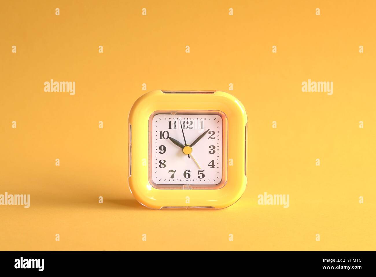 Gelbe Uhr auf gelbem Hintergrund. Mitte des Rahmens. Stockfoto