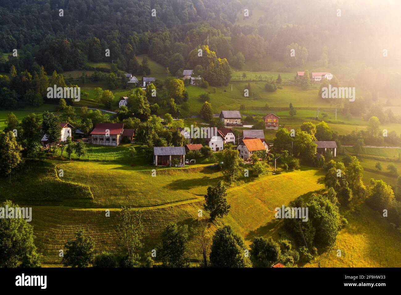 Bukovo, Slowenien - Luftaufnahme eines kleinen Bergdorfes in den slowenischen alpen bei Bukovo an einem sonnigen Sommermorgen. Warme Farben, lange Schatten und V Stockfoto