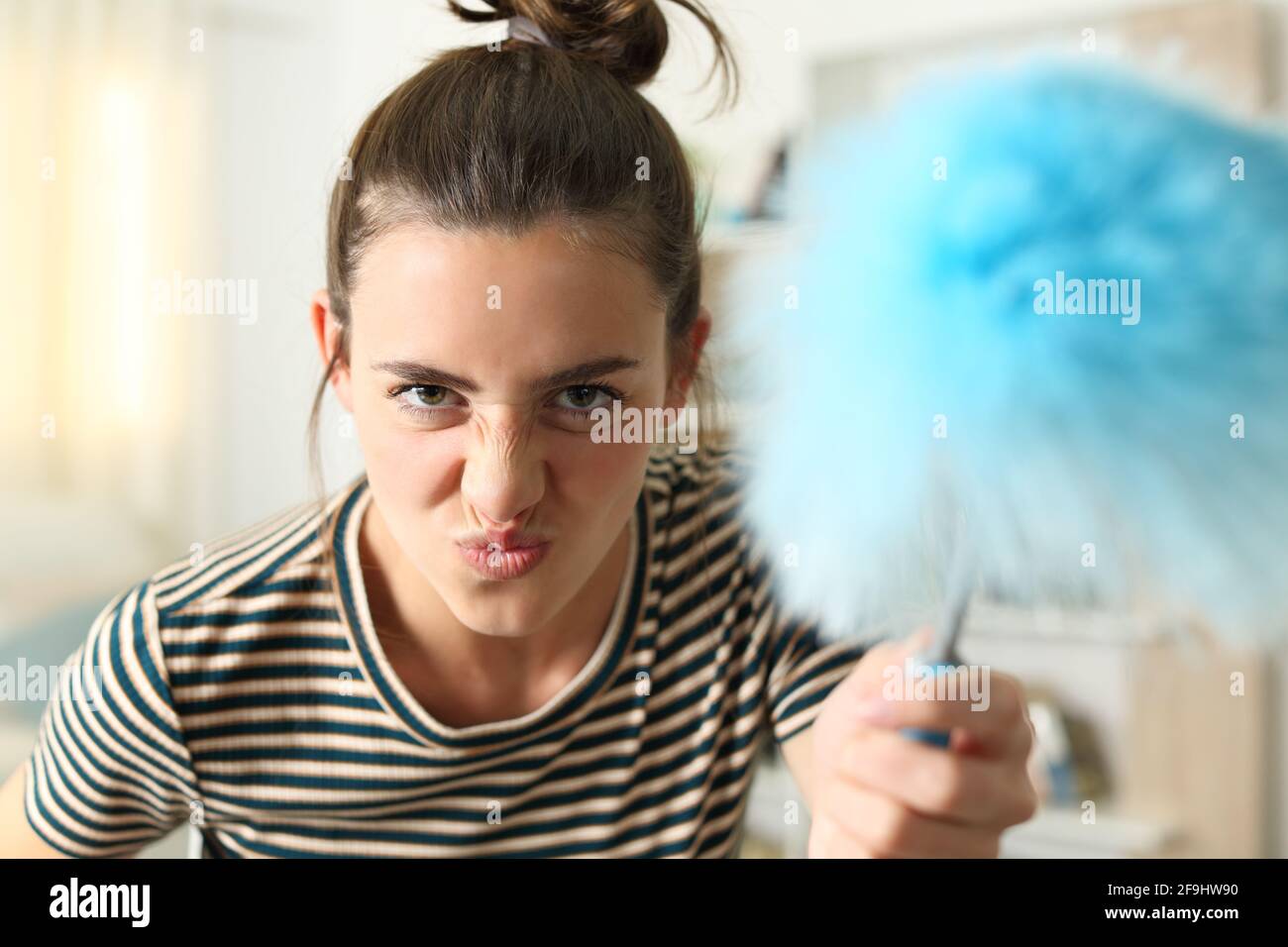 Vorderansicht Porträt einer lustigen Frau Grimacing bedrohlich an Kamera mit Staubwischen zu Hause Stockfoto