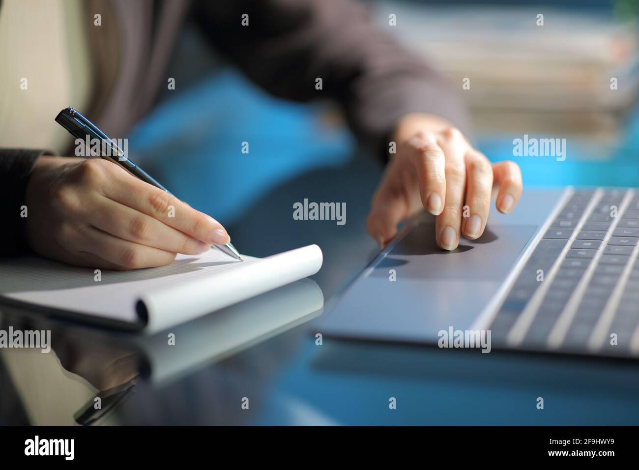 Nahaufnahme einer Frau, die sich Notizen auf dem Notizbuch gemacht hat Mit Laptop in der Nacht zu Hause Stockfoto