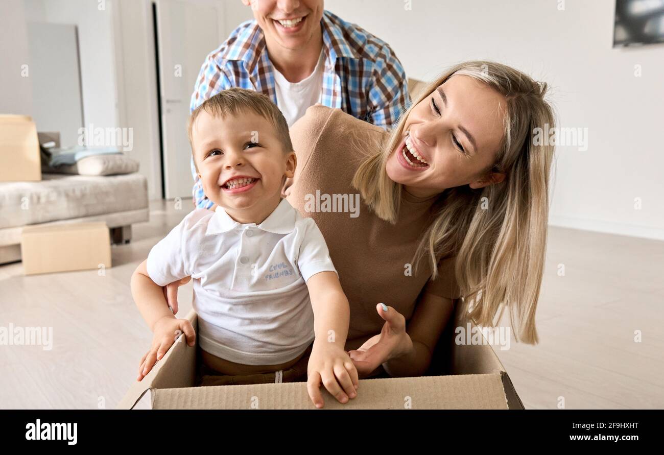 Nette aufgeregt Kind Sohn Reiten in Box am bewegenden Tag mit den Eltern in neuem Zuhause. Stockfoto