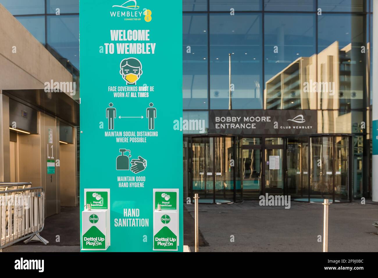 Wembley Park, London, Großbritannien. April 2021. Covid-Sicherheitsmaßnahmen an den Drehkreuzen des Wembley-Stadions. Um die Bobby Moore Statue herum sind Händedesinfektionsstationen und Bodenmarkierungen mit einer Entfernung von 2 Metern zu sehen. Das Nationalstadion veranstaltet im Rahmen des wissenschaftlich geführten Events Research Program (ERP) der Regierung 3 Pilotveranstaltungen (das Finale des Carabao- und FA-Pokals sowie ein Halbfinale des Emirates FA Cup), um in diesem Sommer wieder große Menschenmengen zu gewinnen. Amanda Rose/Alamy Live News Stockfoto