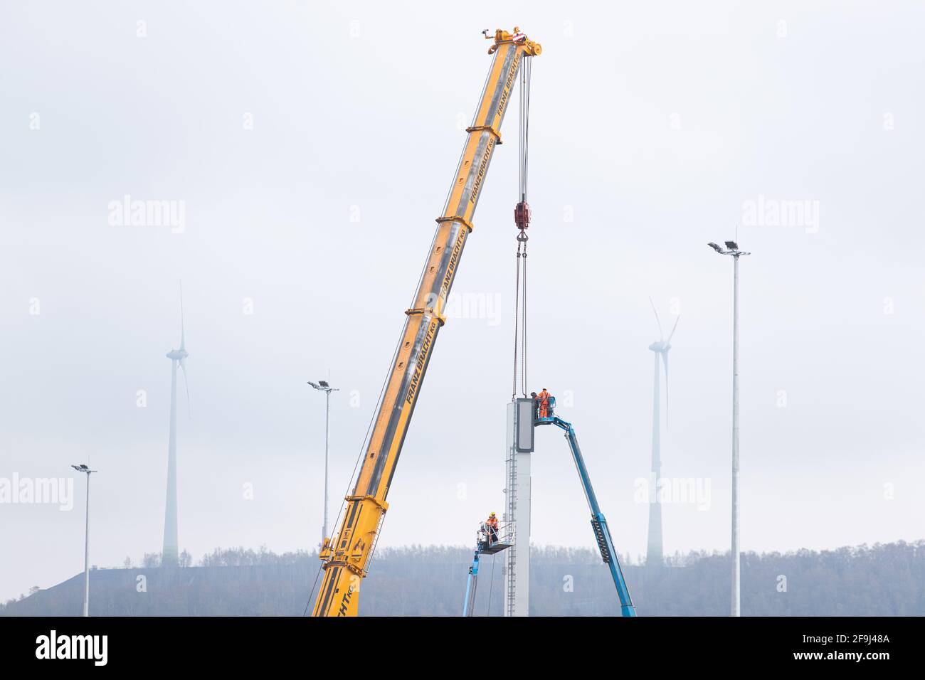 19. April 2021, Niedersachsen, Osnabrück: Arbeiter montieren das Bauteil eines Portalkrans mit einem Spezialkran. Für den Ausbau des Osnabrücker Containerterminals sollen die Arbeiten an der Montage von zwei gut 50 Meter breiten und 40 Meter hohen Portalkranen beginnen. Die Fertigstellung des Containerterminals ist für den Sommer geplant. In Zukunft sollen jährlich bis zu 150,000 Ladeeinheiten von der Straße auf die Schiene verlagert werden. Insgesamt werden 29 Millionen Euro in das Projekt investiert. Foto: Friso Gentsch/dpa Stockfoto