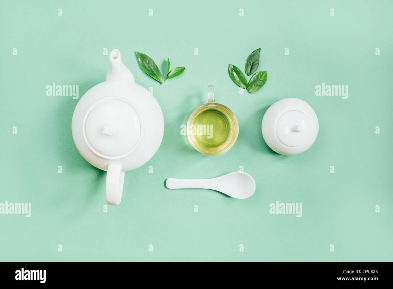 Blick von oben auf eine Reihe von Teegeschirr Teekanne Zucker Schüssel Tasse mit Tee auf grünem Hintergrund Stockfoto